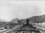 A westbound Santa Fe train pauses at Cajon Siding to cool its braking equipment after descending the pass in March 1943. The original station structures and facilities can be seen to the left of the train.