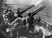 Bofors 40 mm anti-aircraft guns on a MK 12 quadruple mount fire from the deck of the USS Hornet in World War II.