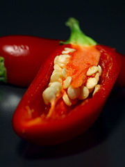A ripe red jalapeño cut open to show the seeds