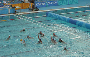 A classic 4-2 man-up situation. The attacking white team has 4 players positioned on 2 metres, and 2 players positioned on 4 metres. The 5 outfield defending blue players try to block shots and prevent a goal being scored for the 20 seconds of man-down play. In the top left corner, the shot clock can be seen, showing 28 seconds remaining in the white attack.